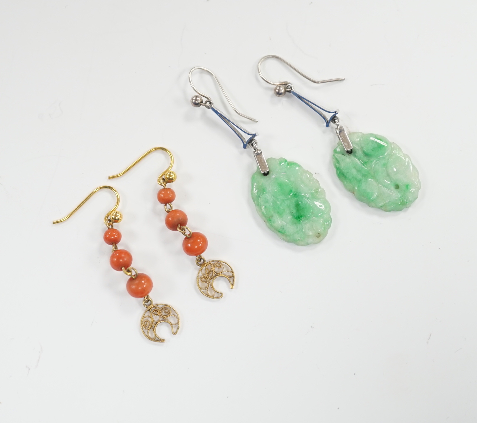 A pair of 9ct white metal and carved oval jade set drop earrings, jade 21mm and a pair of yellow metal and graduated three stone coral bead drop earrings, gross weight 6.2 grams.